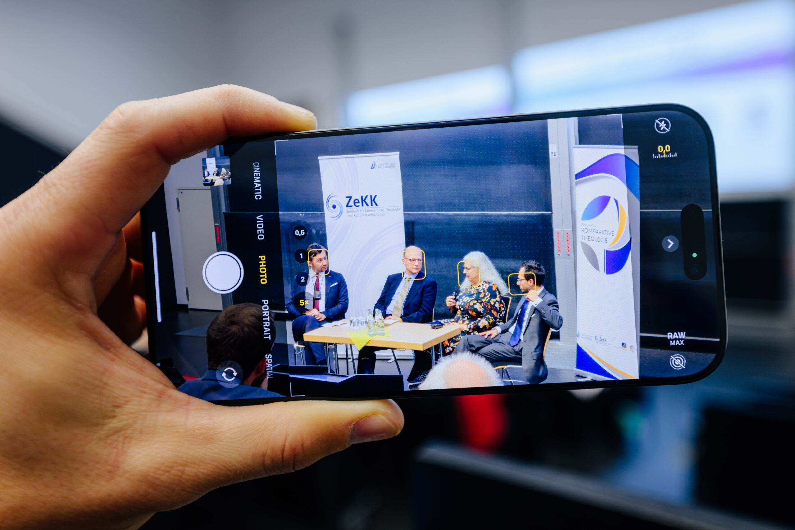 Blick auf Smartphone, auf welchem eine Diskussion mehrerer Personen zu erkennen ist.