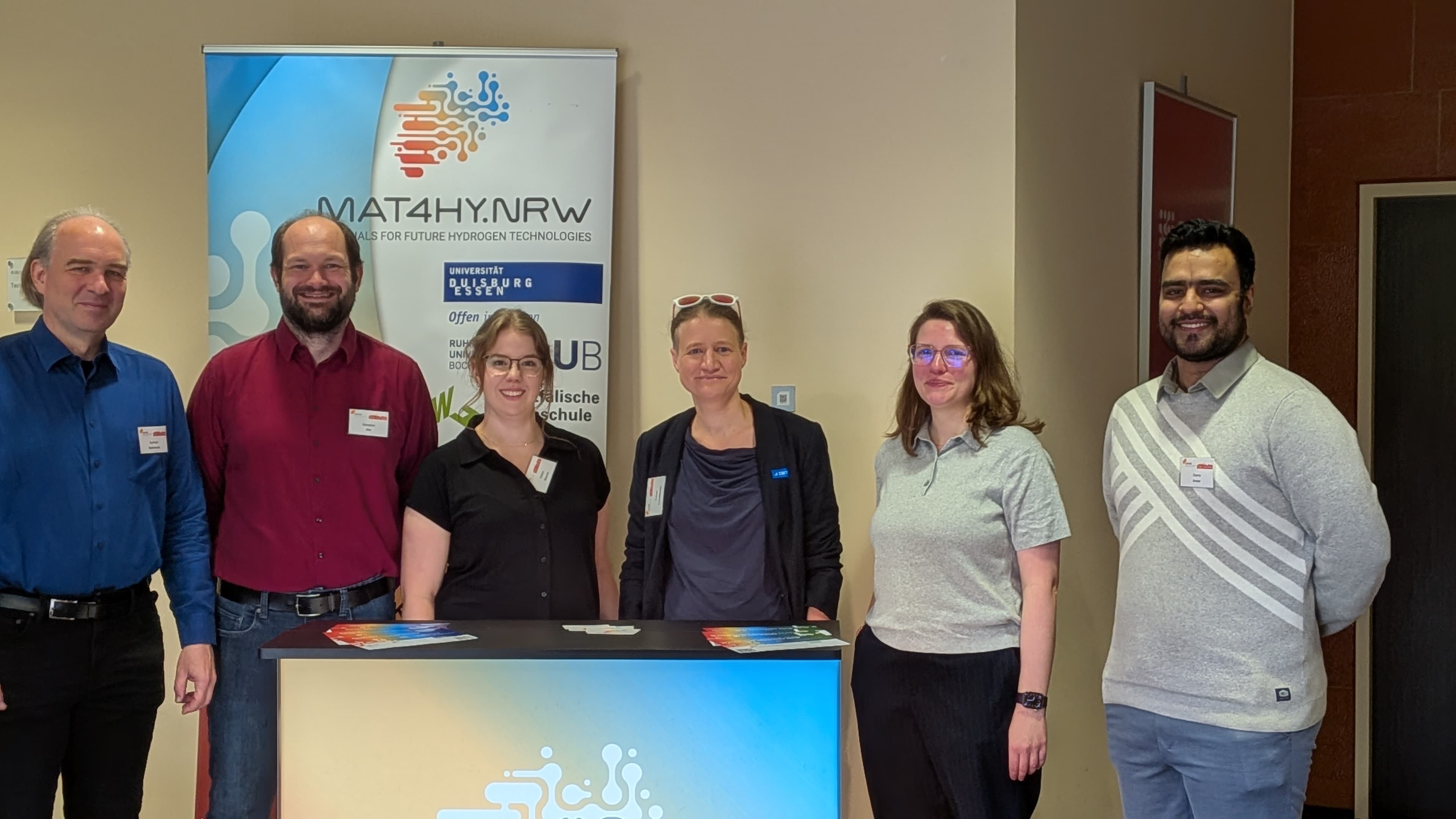 Das Team von MAT4HY.NRW posiert auf der MCIC conference am 22.09.2025 in Bochum vor ihrem eigenen Stand.