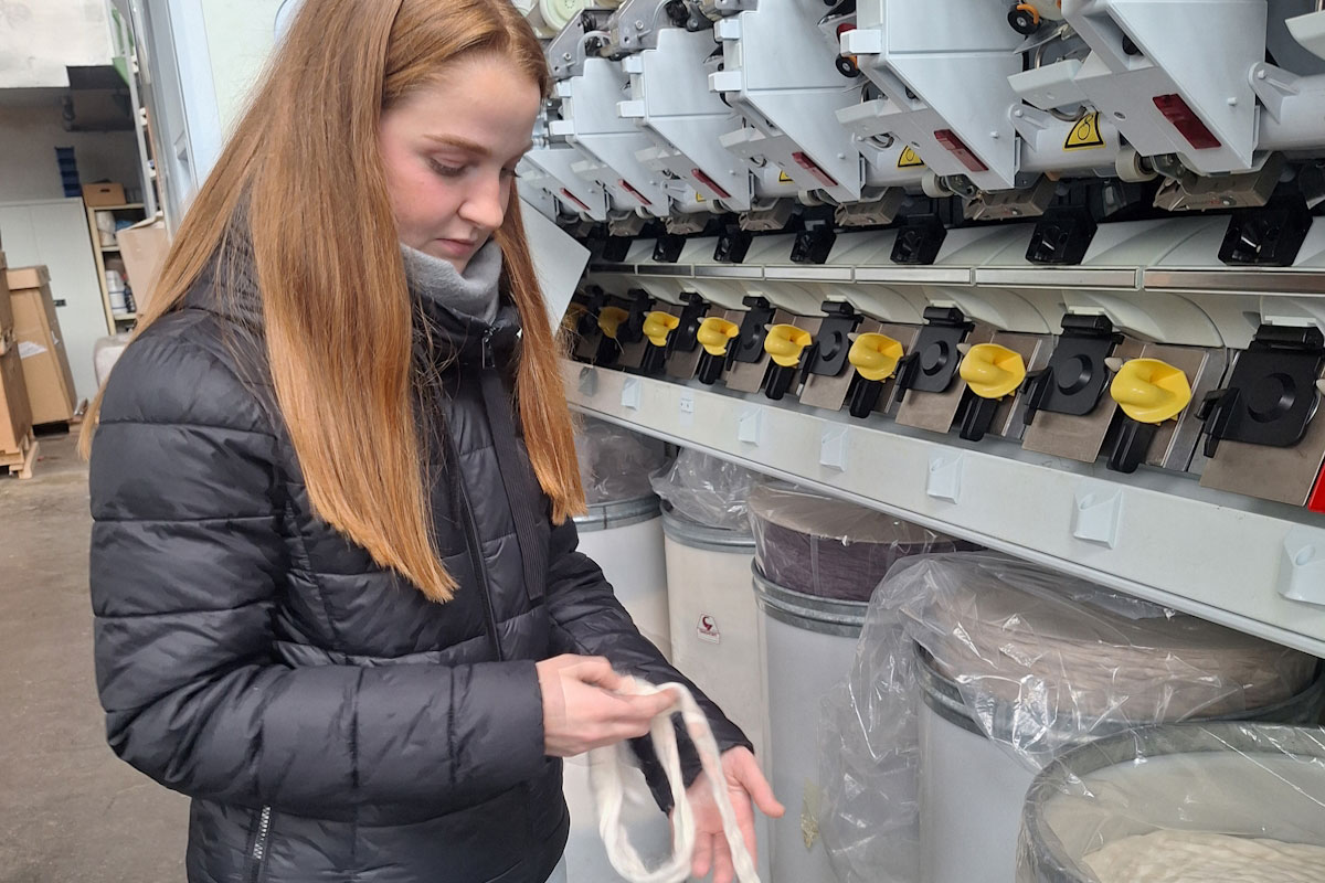 Eine junge Frau begutachtet ein Fadenband aus Baumwolle.
