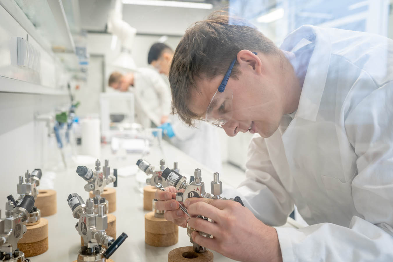 Eine Person steht an einer Laborbank und montiert ein Metallgerät.